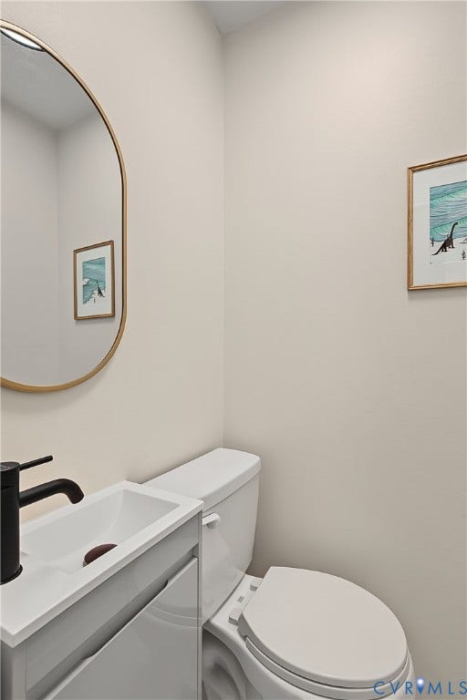 3800 Pheasant Hollow Drive, Henrico, VA 23231 White vanity with integrated rectangular sink, matte black faucet, and oval wall-mounted mirror with gold finish