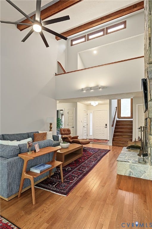 3800 Pheasant Hollow Drive, Henrico, VA 23231 Vaulted ceilings with exposed wood beams, stone-faced fireplace, transom windows, wood-finish flooring, and multi-blade ceiling fan