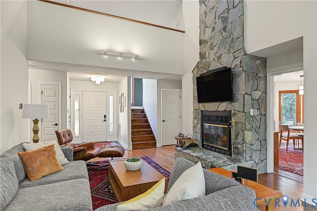 3800 Pheasant Hollow Drive, Henrico, VA 23231 High-ceilinged living area featuring a floor-to-ceiling natural stone fireplace, wood-finish flooring, and a wooden staircase