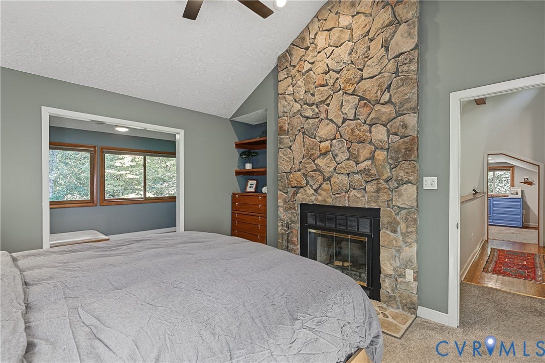 3800 Pheasant Hollow Drive, Henrico, VA 23231 Vaulted ceiling with a ceiling fan, full-height natural stone fireplace, and built-in wood shelving