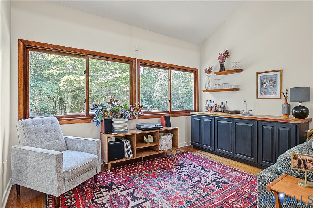 3800 Pheasant Hollow Drive, Henrico, VA 23231 Vaulted ceilings, large windows with wood trim, built-in cabinetry, integrated wet bar with sink, and floating wood shelving