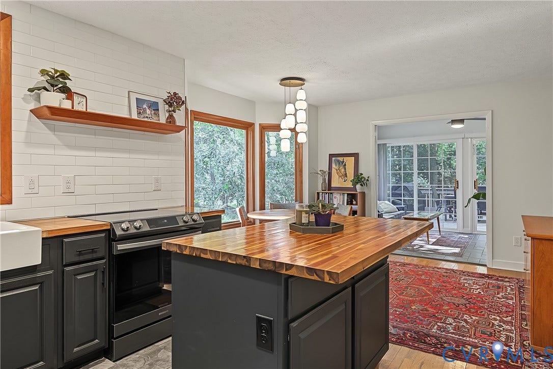 3800 Pheasant Hollow Drive, Henrico, VA 23231 Kitchen featuring a central island with a wood-finish countertop, subway tile backsplash, farmhouse-style sink, floating wood shelf, and multi-light pendant fixture