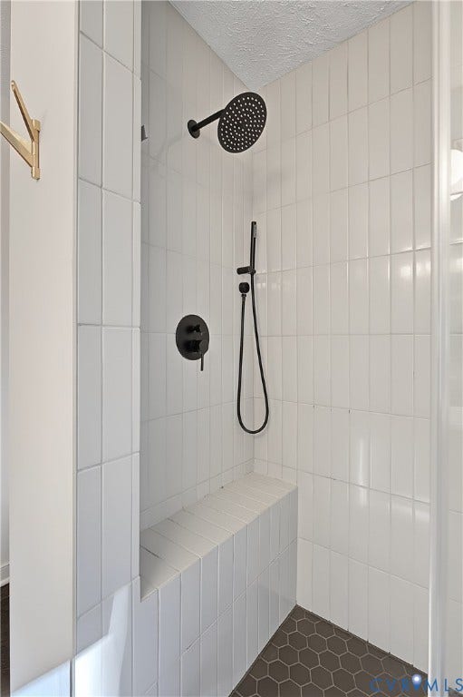 3800 Pheasant Hollow Drive, Henrico, VA 23231 Walk-in shower featuring vertical white subway tile walls, built-in tiled bench, hexagonal floor tiling, and matte black rain-style shower head with coordinating handheld wand