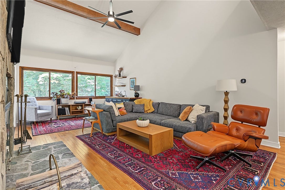 3800 Pheasant Hollow Drive, Henrico, VA 23231 Vaulted ceiling with exposed wooden beam, floor-to-ceiling natural stone fireplace, wood-finish flooring, and ceiling fan with integrated lighting