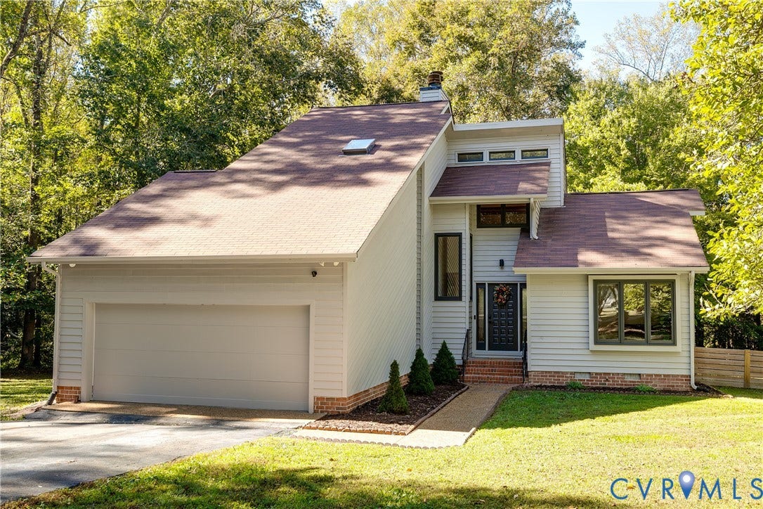 3800 Pheasant Hollow Drive, Henrico, VA 23231 Multi-level exterior featuring light-toned horizontal siding, a prominent roofline with a skylight, a brick foundation perimeter, and an attached two-car garage