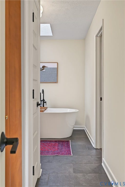 3800 Pheasant Hollow Drive, Henrico, VA 23231 Freestanding soaking tub featuring a matte black floor-mounted faucet and large-format grey tile flooring