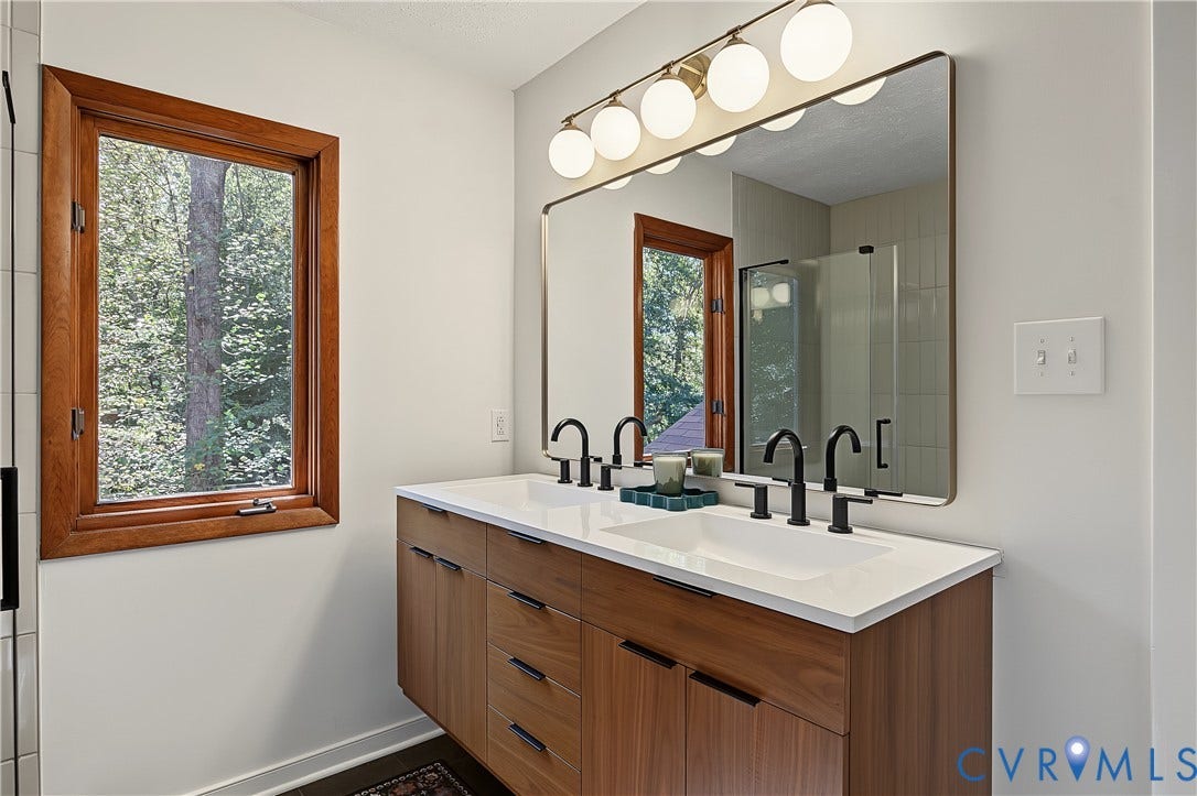3800 Pheasant Hollow Drive, Henrico, VA 23231 Floating vanity featuring wood-finish cabinetry, a white countertop with integrated dual sinks, matte black widespread faucets, and a multi-globe light fixture