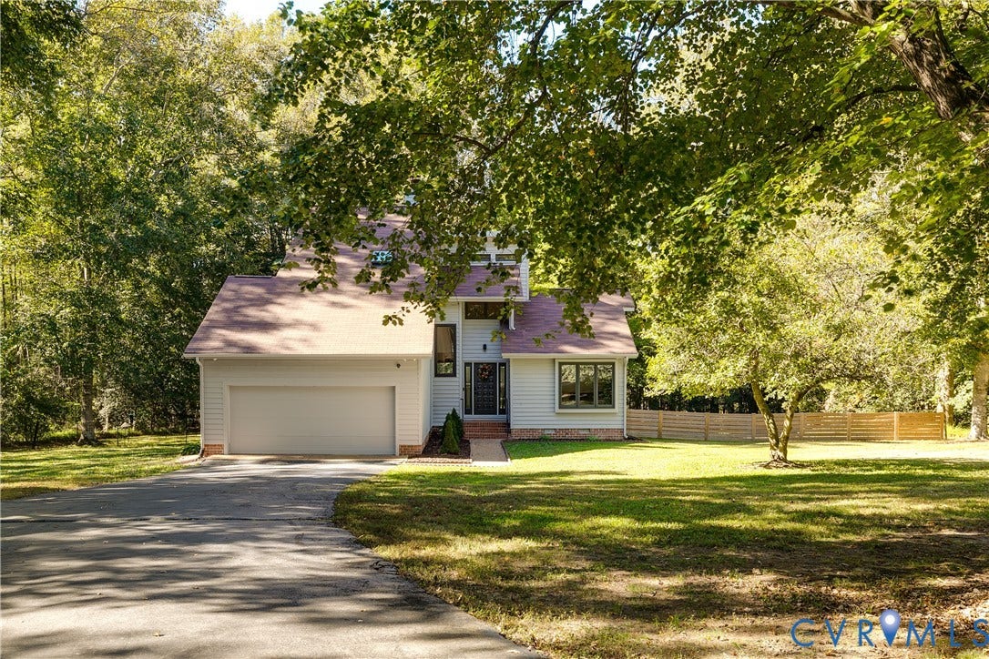 3800 Pheasant Hollow Drive, Henrico, VA 23231 Two-story exterior featuring light-toned horizontal siding, a gabled roofline, an attached two-car garage, and a wood-slat privacy fence on a lot with mature trees