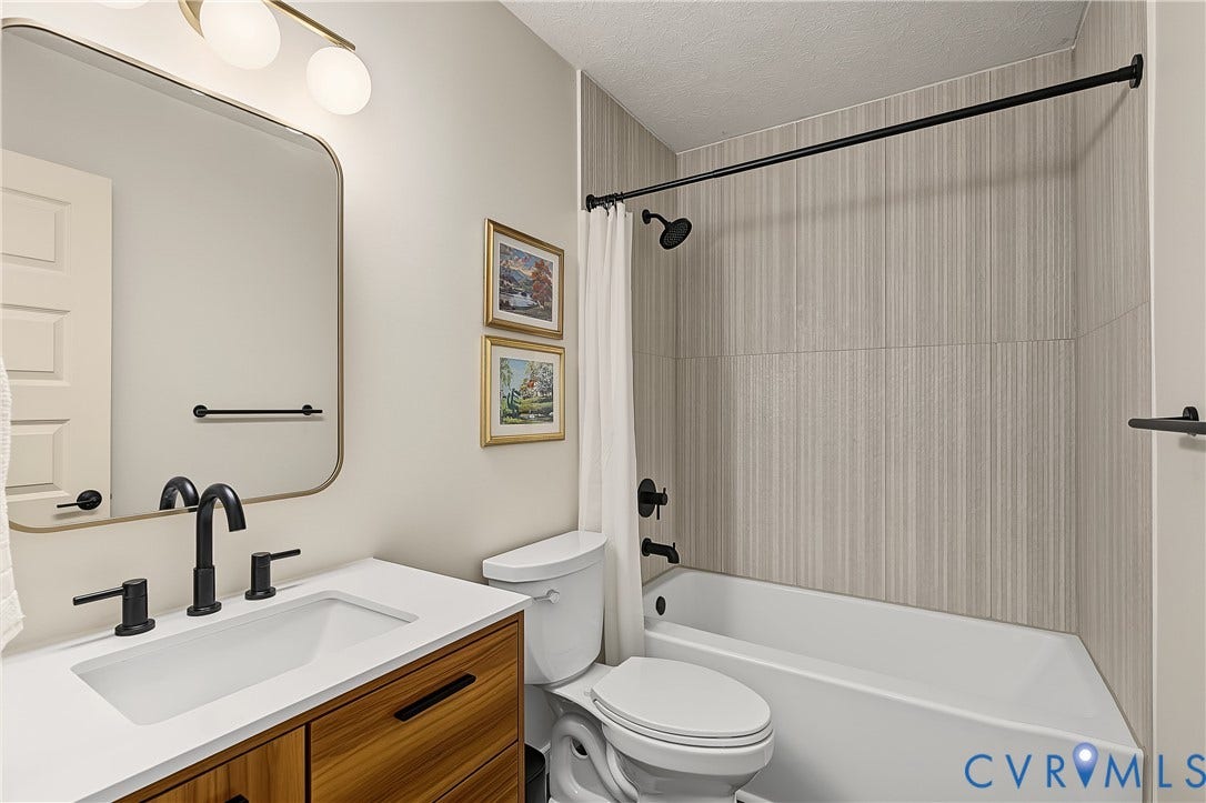3800 Pheasant Hollow Drive, Henrico, VA 23231 Bathroom featuring a wood-finish vanity with a rectangular sink, quartz countertop, matte black fixtures, and a shower-tub combination with vertical tile surround