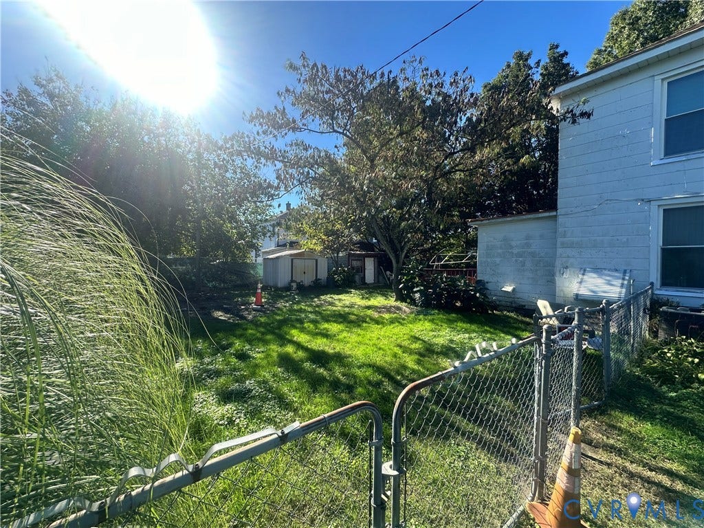 5 N Daisy Avenue, Henrico, VA 23075 Rear exterior featuring a fenced yard, mature trees, and a detached storage structure