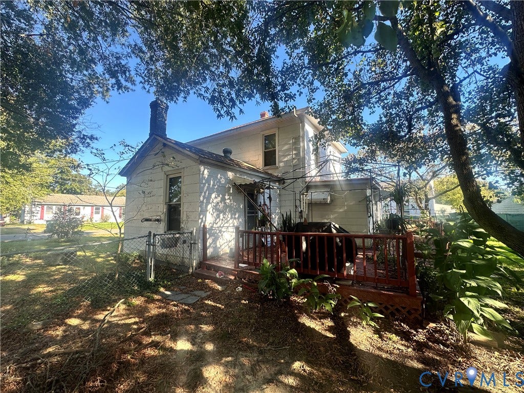 5 N Daisy Avenue, Henrico, VA 23075 Two-story exterior featuring white horizontal siding, a brick chimney, a raised wooden deck with railings, and mature surrounding trees