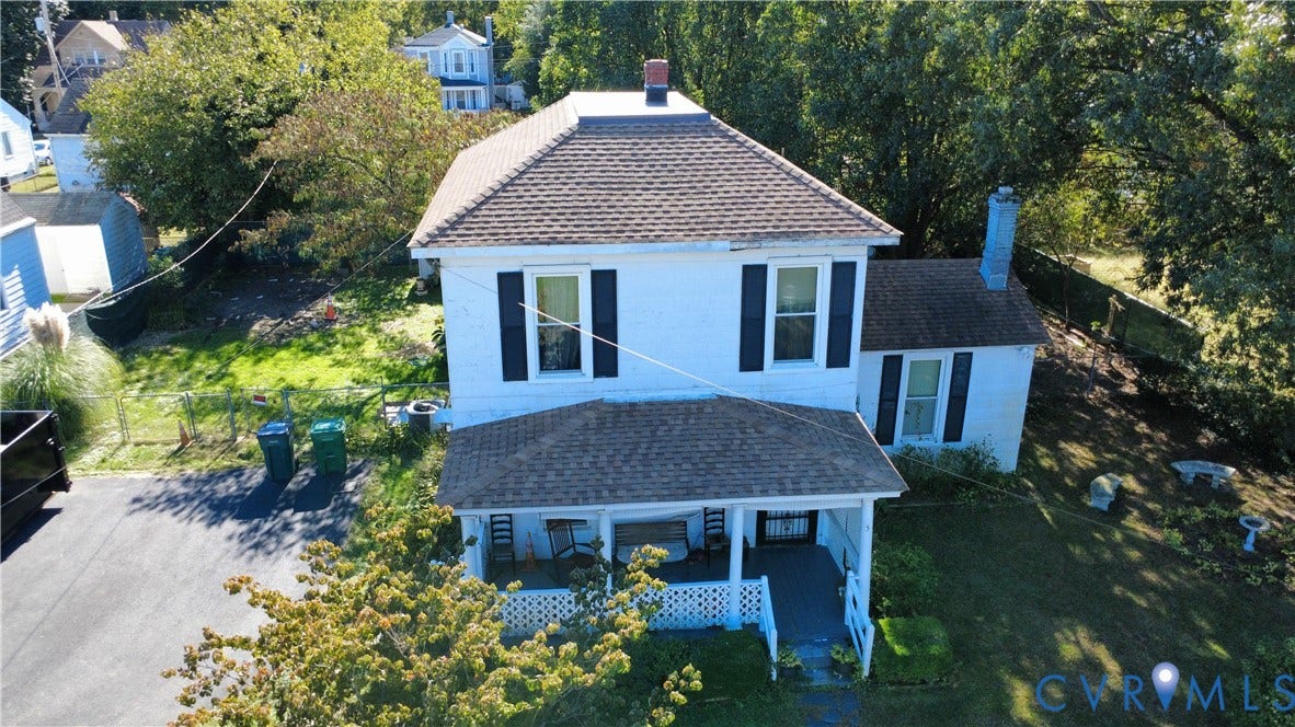 5 N Daisy Avenue, Henrico, VA 23075 Two-story detached home featuring a hipped roof, covered front porch with lattice skirting, asphalt-paved driveway, and exterior chimney