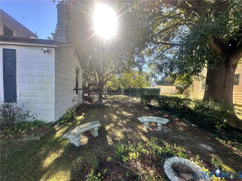5 N Daisy Avenue, Henrico, VA 23075 Rear yard featuring mature trees, concrete masonry benches, a circular stone fire pit, and chain-link perimeter fencing