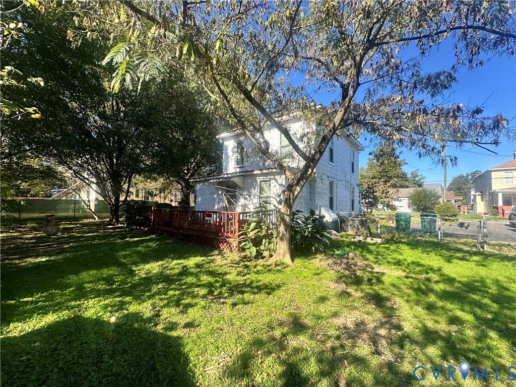 5 N Daisy Avenue, Henrico, VA 23075 Two-story residence featuring light-colored siding, a tiered wooden deck, chain-link fencing, and mature trees