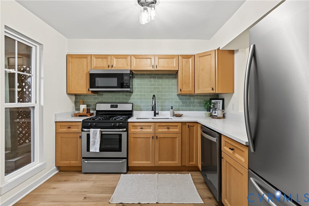 10272 Iron Mill Road, North Chesterfield, VA 23235 Kitchen featuring shaker-style wood cabinetry, stainless steel appliances, white solid-surface countertops, sage green subway tile backsplash, and wood-finish flooring
