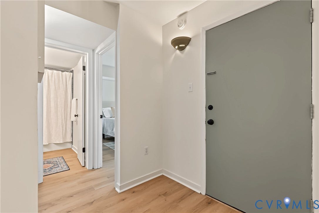 10272 Iron Mill Road, North Chesterfield, VA 23235 Entryway featuring wood-finish flooring, a matte grey door with black hardware, and a wall-mounted light fixture