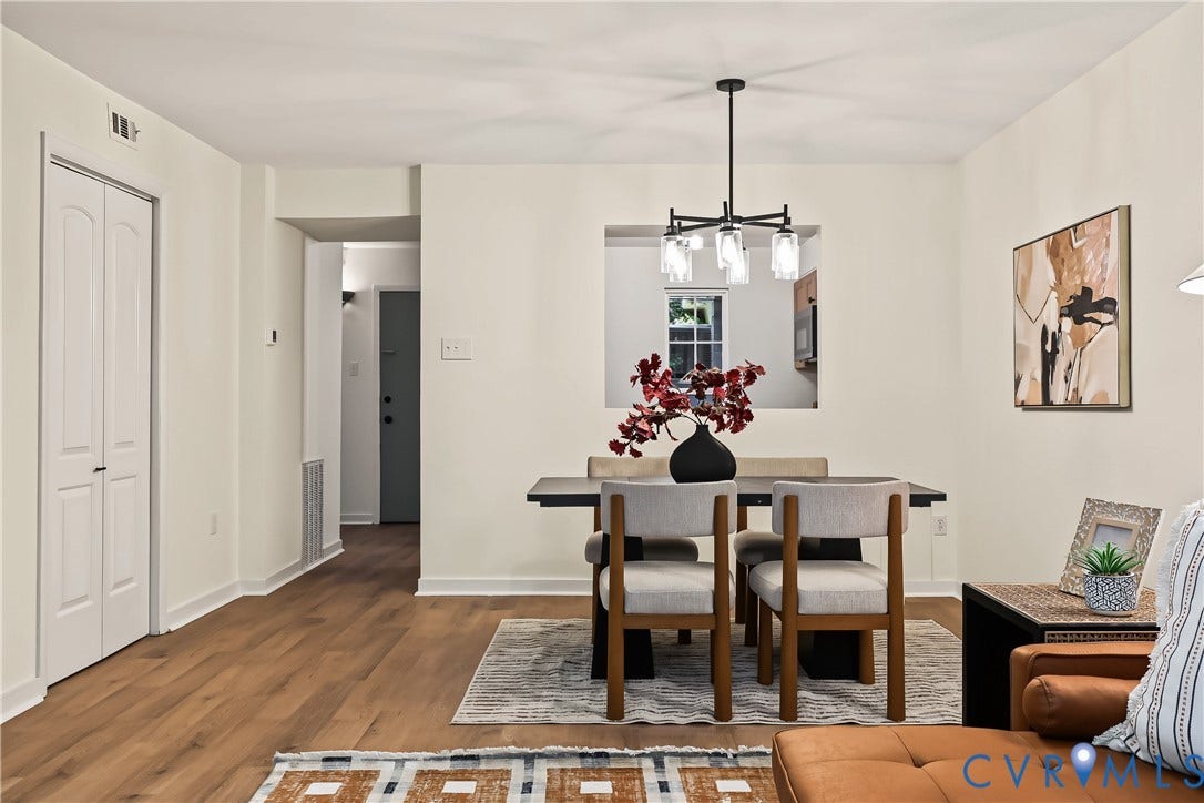 10272 Iron Mill Road, North Chesterfield, VA 23235 Open-concept area featuring wood-finish flooring, a matte black multi-arm chandelier with glass globe shades, and a wall cutout providing transparency to the kitchen