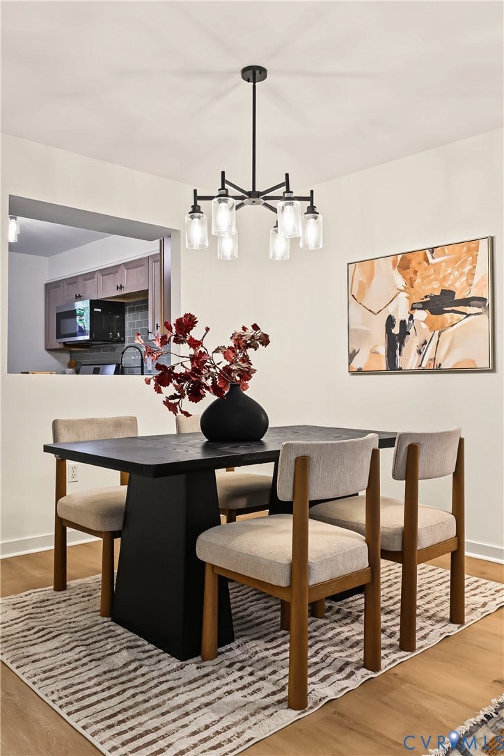 10272 Iron Mill Road, North Chesterfield, VA 23235 Dining space featuring wood-finish flooring, a six-light black metal chandelier with glass shades, and a structural pass-through opening
