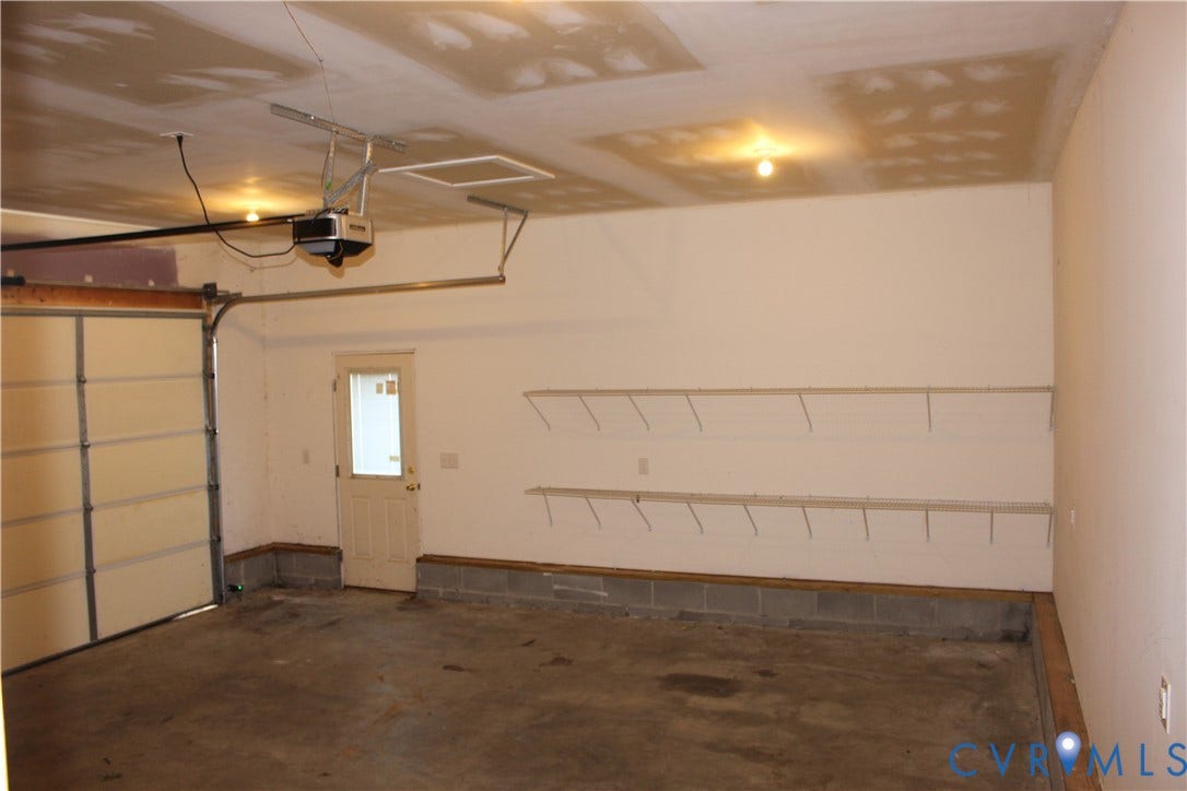 118 Clements Drive, Essex, VA 22560 Garage space featuring a concrete floor, automated overhead door opener, exterior access door with window inset, and two levels of wall-mounted wire shelving