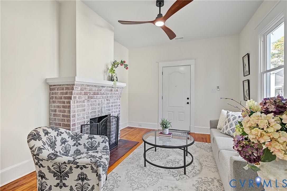 3500 Stockton Street, Weisigers Plan, Richmond, VA 23224 Living area featuring a brick fireplace with a mantle, wood-finish flooring, and a modern ceiling fan with integrated lighting