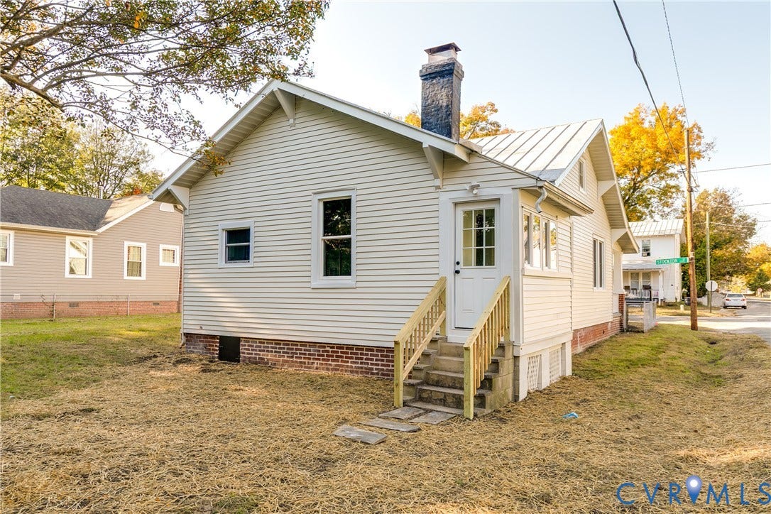 3500 Stockton Street, Weisigers Plan, Richmond, VA 23224 Light-colored vinyl siding, brick foundation, metal roof, exterior brick chimney, and wooden staircase with railings