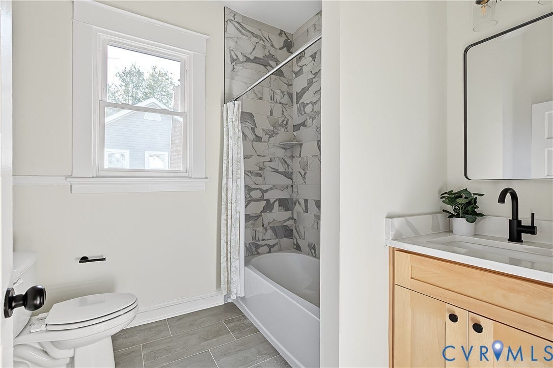 3500 Stockton Street, Weisigers Plan, Richmond, VA 23224 Bathroom featuring a wood-finish vanity with a stone-surfaced countertop, matte black faucet, walk-in tub with large-format patterned wall tile, and grey tile flooring