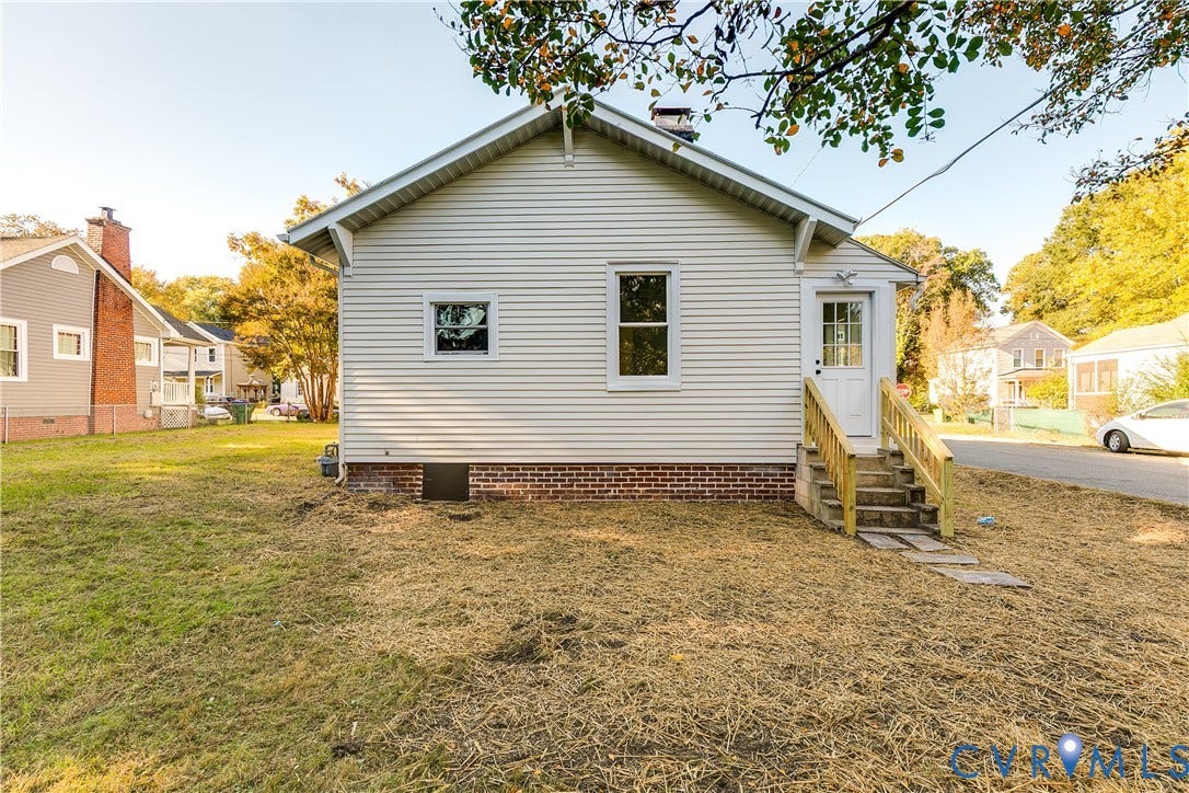 3500 Stockton Street, Weisigers Plan, Richmond, VA 23224 Exterior side elevation featuring horizontal vinyl siding, a brick foundation, a chimney, and a wooden staircase leading to a glass-panel entry door