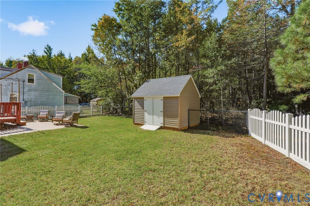 308 N Snead Street, #A, Ashland, VA 23005 Backyard featuring a concrete stamped patio, detached storage shed with a shingled roof, white picket fencing, and a perimeter chain-link fence