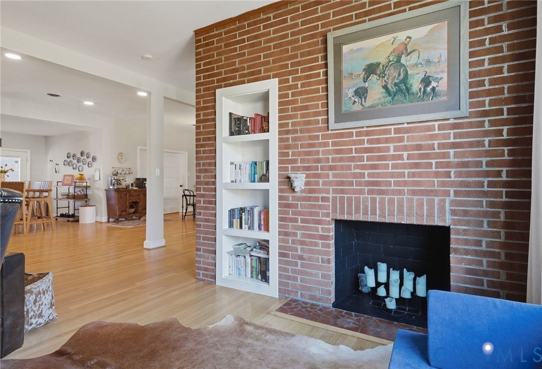 9 E 31st Street, Richmond, VA 23224 Floor-to-ceiling red brick fireplace featuring a recessed built-in shelving unit, black firebox, and stone hearth, complemented by wood-finish flooring