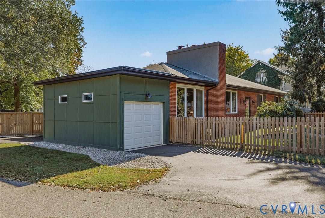 9 E 31st Street, Richmond, VA 23224 Exterior featuring red brick masonry, green panel siding, a single-car garage, and a wood picket fence