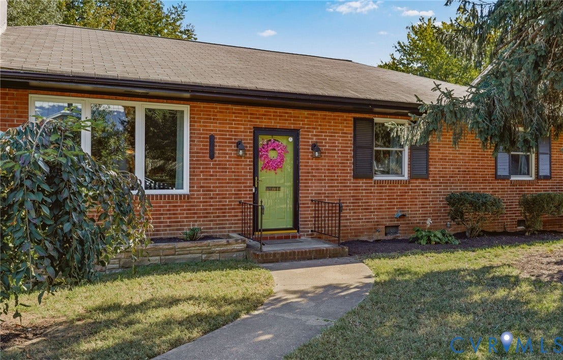 9 E 31st Street, Richmond, VA 23224 Red brick exterior featuring dark shutter accents, multi-pane windows, and a stone-masonry planter bed