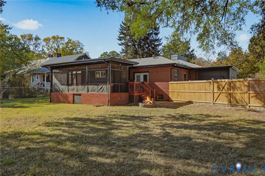 9 E 31st Street, Richmond, VA 23224 Exterior featuring a red brick facade, an enclosed screened porch, a wood deck with stairs, and a privacy fence