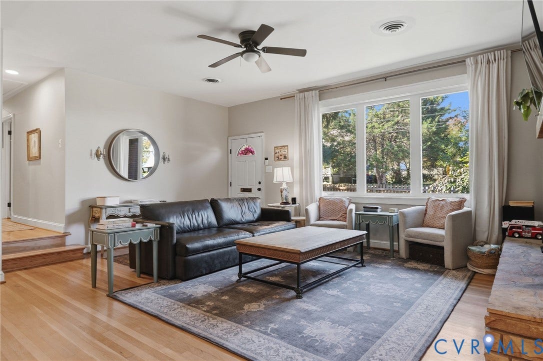 9 E 31st Street, Richmond, VA 23224 Living area featuring wood-finish flooring, a multi-pane picture window, a central ceiling fan, and a stone-clad hearth