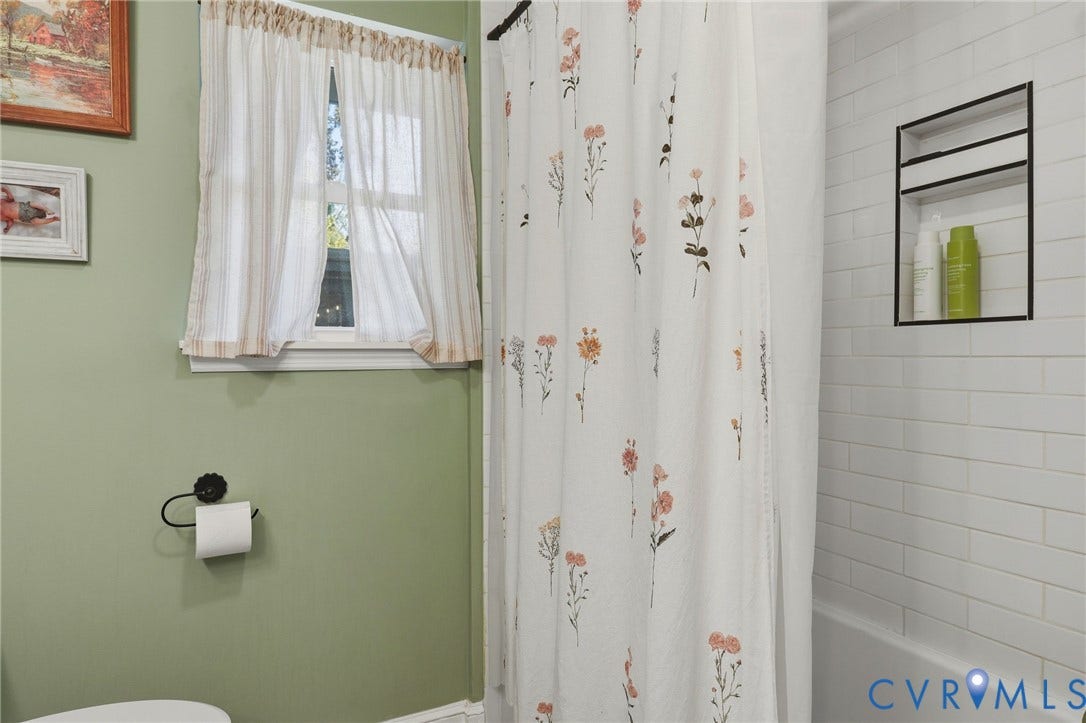9 E 31st Street, Richmond, VA 23224 Bathroom featuring white subway tile wall surround, built-in recessed shower niche with black trim, and a window with a dedicated sill