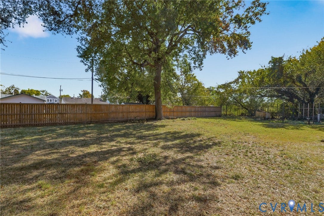 9 E 31st Street, Richmond, VA 23224 Expansive backyard featuring a wood-panel fence, open lawn space, and mature trees