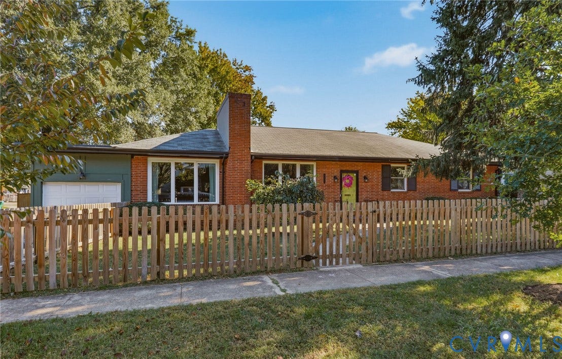 9 E 31st Street, Richmond, VA 23224 Single-story exterior featuring a brick facade, exterior chimney, wooden picket fence, attached garage, and multi-pane windows