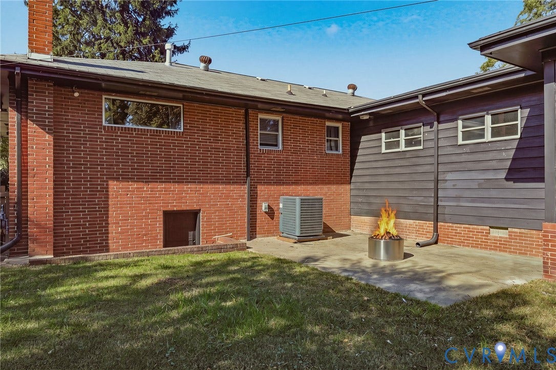 9 E 31st Street, Richmond, VA 23224 Exterior rear facade featuring red brick and dark horizontal siding, concrete patio, and lawn area