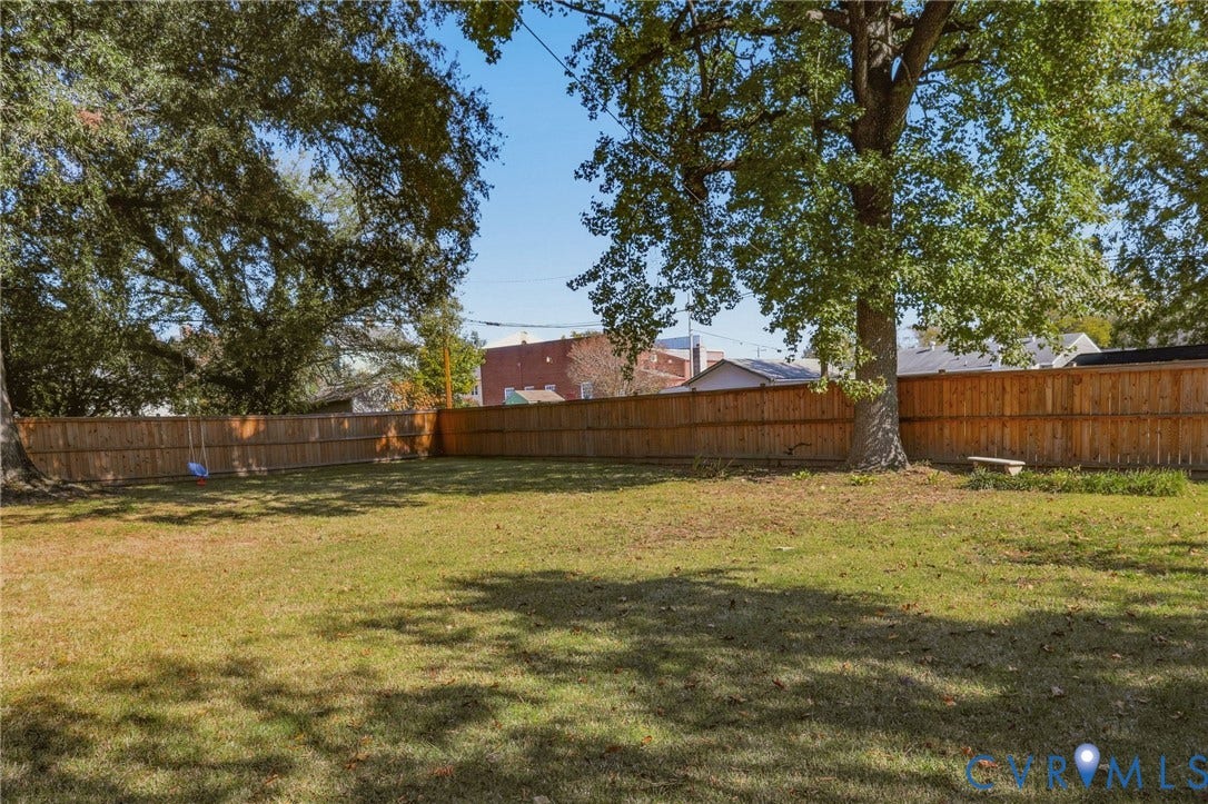 9 E 31st Street, Richmond, VA 23224 Expansive backyard featuring a fenced perimeter, mature trees, and a level grass lawn
