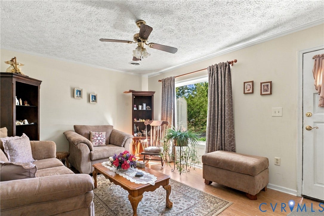 8840 Black Creek Road, New Kent, VA 23141 Neutral-toned walls, wood-finish flooring, ceiling fan with integrated lighting, and a large window providing natural illumination