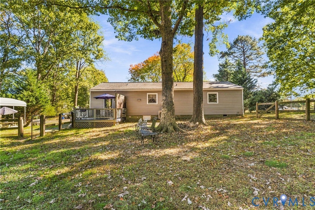 8840 Black Creek Road, New Kent, VA 23141 Exterior featuring horizontal siding, a wooden deck, and a post-and-rail fence set within a partially wooded lot