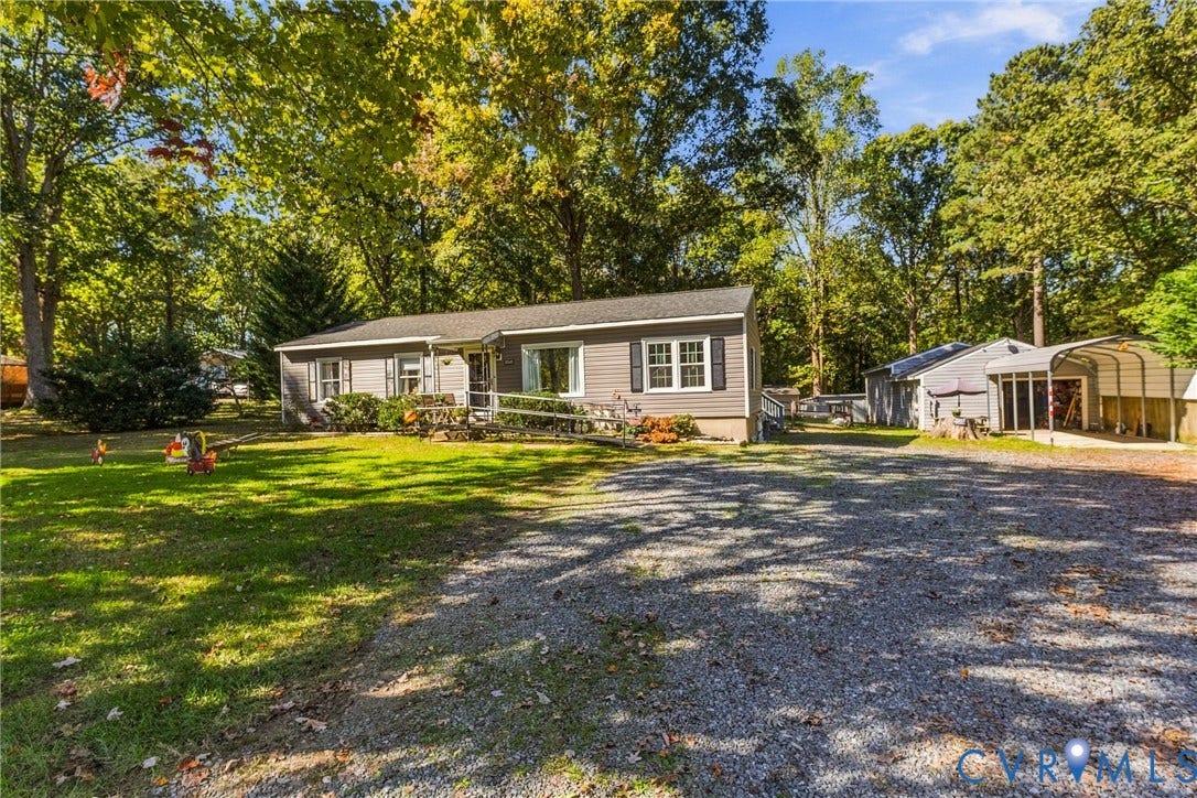 8840 Black Creek Road, New Kent, VA 23141 Single-story residence with horizontal siding, multi-pane windows, decorative shutters, a gravel driveway, and a detached carport