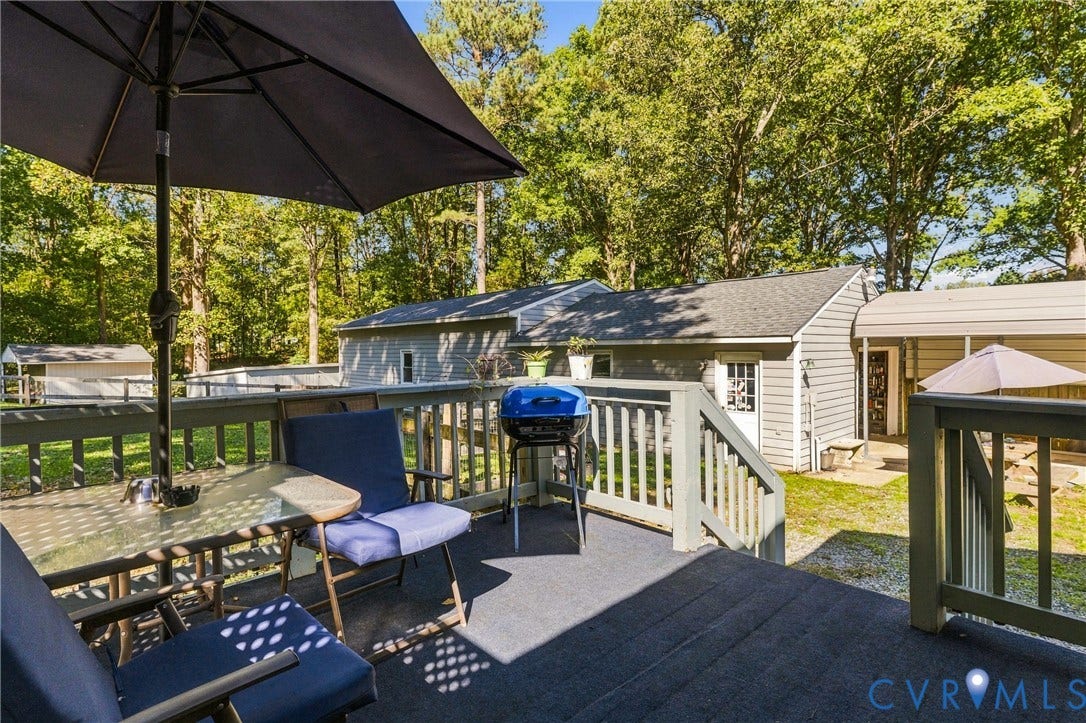 8840 Black Creek Road, New Kent, VA 23141 Elevated wooden deck featuring matching railings and stairs, exterior siding, and a metal-roofed carport