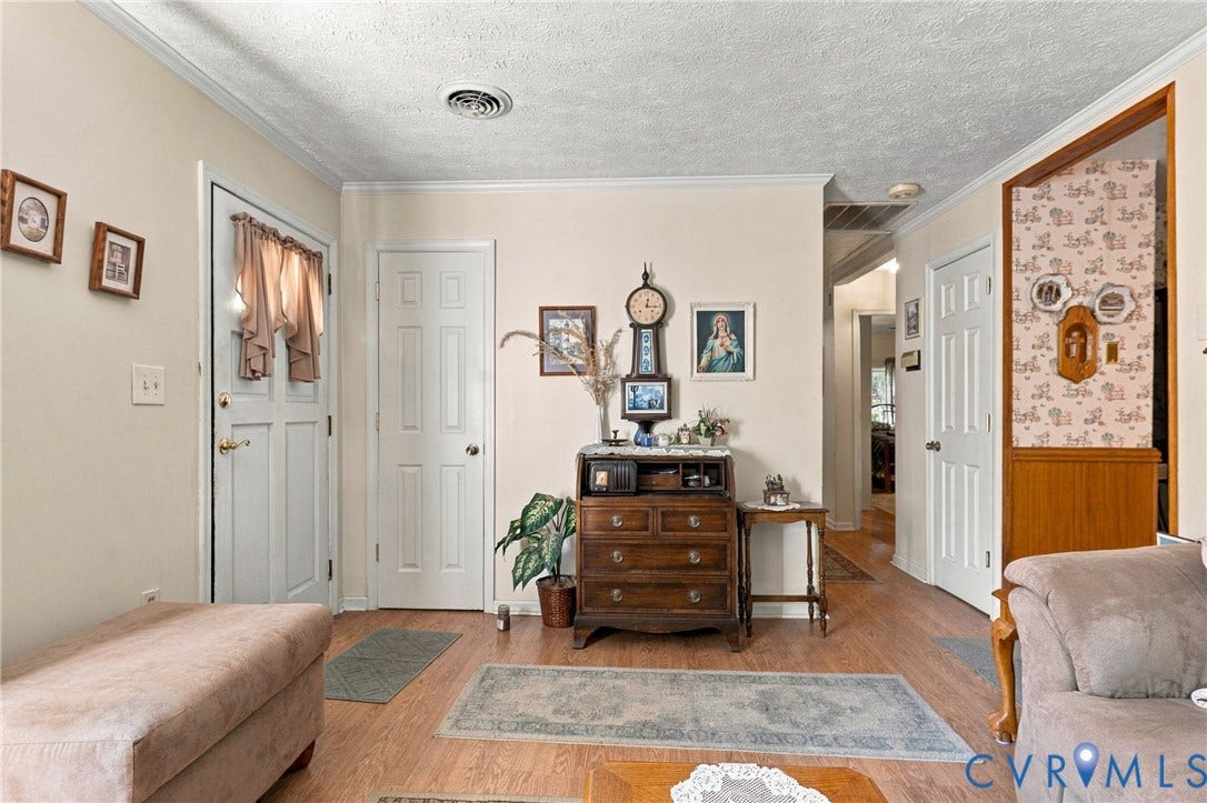 8840 Black Creek Road, New Kent, VA 23141 Interior entryway featuring light-toned wood-finish flooring, six-panel interior doors, and a decorative wainscot paneled partition
