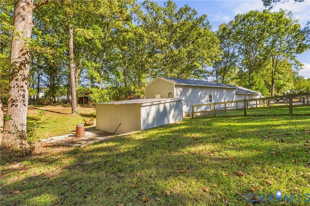 8840 Black Creek Road, New Kent, VA 23141 Expansive grounds featuring mature shade trees, a detached storage structure with metal siding, horizontal vinyl exterior siding, and perimeter post-and-rail fencing
