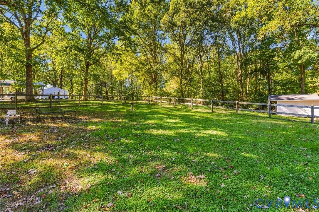 8840 Black Creek Road, New Kent, VA 23141 Expansive backyard featuring a post-and-rail perimeter fence, mature trees, and a grass lawn