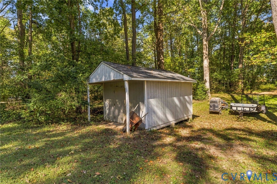 8840 Black Creek Road, New Kent, VA 23141 Storage shed with vertical wood siding, asphalt shingle gable roof, and open-front bay