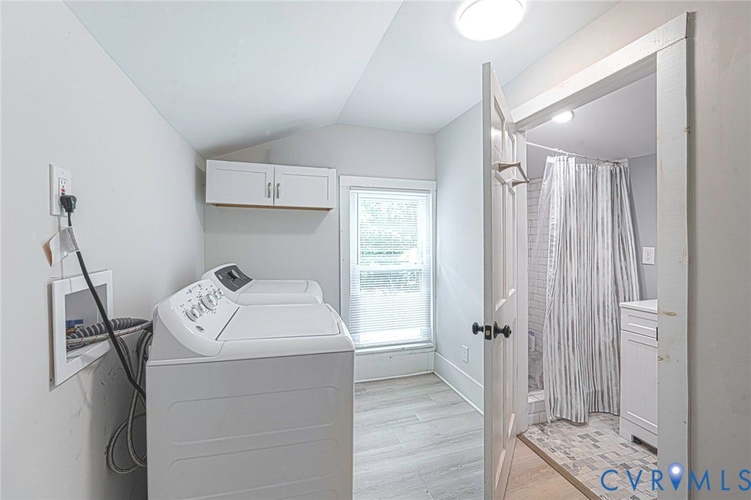 1818 Arlington Road, Hopewell, VA 23860 Utility room featuring wood-finish flooring, white wall-mounted cabinetry, a window, and an entry to a bathroom equipped with a shower and vanity