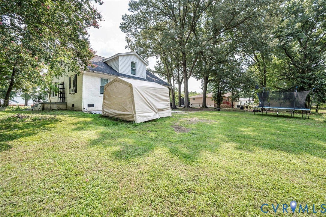 1818 Arlington Road, Hopewell, VA 23860 Expansive backyard featuring mature shade trees, a white-painted brick exterior, and a multi-level roofline