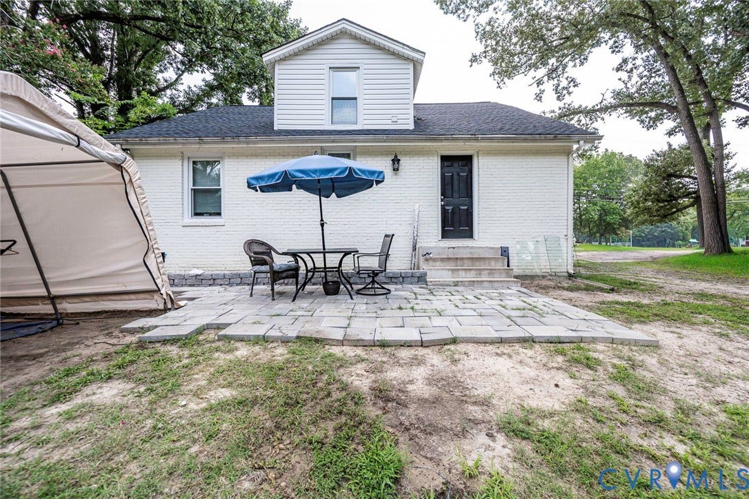 1818 Arlington Road, Hopewell, VA 23860 Exterior featuring white brick siding, a stone paver patio, dormer window, and an attached entry with concrete steps