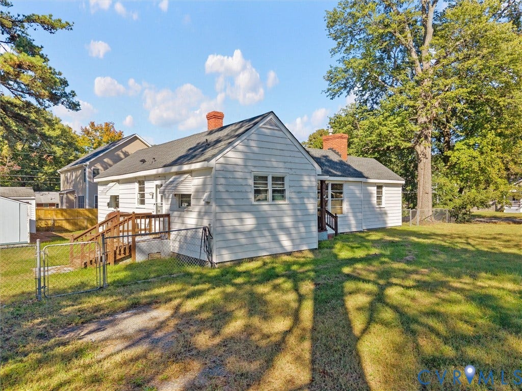 2900 Overton Road, Henrico, VA 23228 Exterior featuring white siding, two brick chimneys, a wood deck, chain-link fencing, and mature trees on a level lot